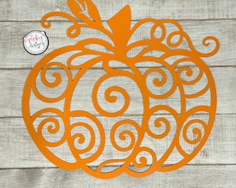 May include: Orange metal pumpkin cutout with a swirling design. The pumpkin is on a light wood background.