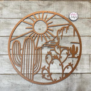 May include: A brown wooden wall hanging with a cutout design of a desert scene. The design includes a sun, a cactus, and a mountain range.