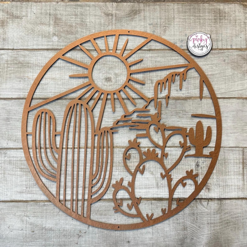 May include: A brown wooden wall hanging with a cutout design of a desert scene. The design includes a sun, a cactus, and a mountain range.