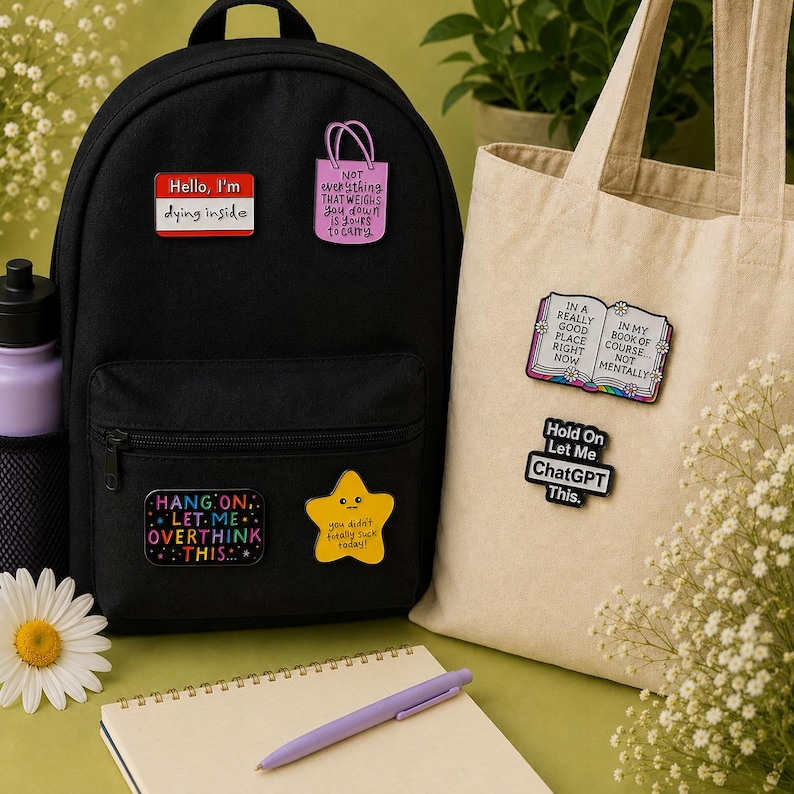 Funny mental health enamel pin badges displayed on a black backpack and cream canvas tote bag. Features Hello I'm Dying Inside, Not Everything That Weighs You Down Is Yours to Carry, Hang On Let Me Overthink This, You Didn't Totally Suck Today, In a Really Good Place Right Now Not Mentally book pin, and Hold On Let Me ChatGPT This enamel badge. Perfect gift for teachers, coworkers, students, office lanyards, backpacks and tote bags.