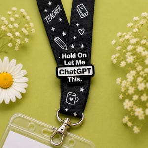 Hold On Let Me ChatGPT This hard enamel pin attached to a black teacher lanyard on a soft sage green background. Funny teacher badge perfect for lanyards, staff IDs, school bags and classroom accessories.