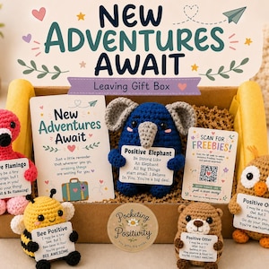 May include: A cardboard gift box labelled New Adventures Await containing five crocheted animals: a pink flamingo, a yellow and black bee, a blue elephant, a brown otter, and a tan owl. Each animal holds a card with positive text.