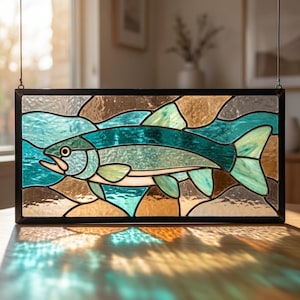 May include: A rectangular stained glass panel featuring a fish swimming through water. The fish is rendered in shades of teal and light blue, while the surrounding water is depicted with textured blue and brown glass pieces, all encased in a black frame.
