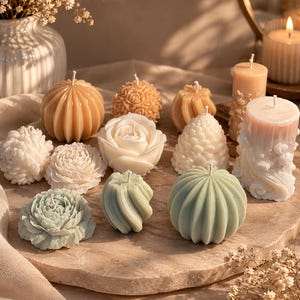 Peut inclure: Une collection de bougies en cire aux formes variées, incluant des designs floraux, sphériques et côtelés. Les bougies sont déclinées dans des tons doux de blanc, crème, beige et vert sauge pâle, chacune dotée d'une mèche en coton.