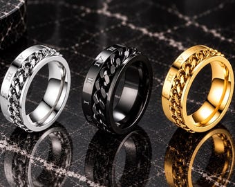 May include: Three rings in silver, black, and gold tones, each featuring a central rotating chain link band. The outer edges of the rings are engraved with Roman numerals, including I, II, III, and IV, visible on the metallic surfaces of the bands.