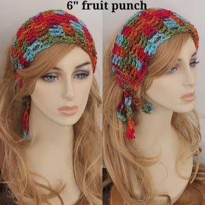 May include: A 6" fruit punch crochet headscarf featuring a variegated yarn pattern in shades of red, orange, green, and blue. The head covering has an open-knit texture with tie-ends on the sides, displaying a colorful, multi-toned design.
