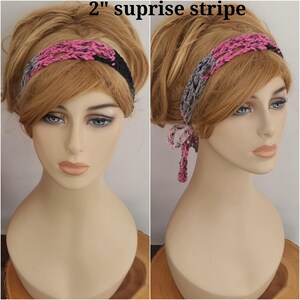 May include: A 2" suprise stripe crochet headband featuring a variegated pattern of pink, grey, and black yarn. The accessory has an open-weave design and includes two thin ties at the back that hang down, allowing for an adjustable fit around the head.
