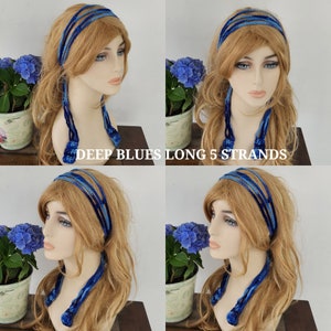 May include: A blue crocheted headband with five long strands hanging down. The headband is worn by a model with long blonde hair. The text "DEEP BLUES LONG 5 STRANDS" is visible in the image.
