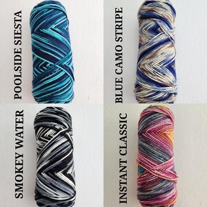 May include: Four skeins of yarn arranged in a grid. Top left is Poolside Siesta in shades of blue and teal. Top right is Blue Camo Stripe in blue, tan, and brown. Bottom left is Smokey Water in black, gray, and white. Bottom right is Instant Classic in pink, orange, and purple.