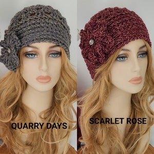 May include: Two crocheted hats with flower embellishments. The hat on the left is gray with the text "Quarry Days" and the hat on the right is burgundy with the text "Scarlet Rose".