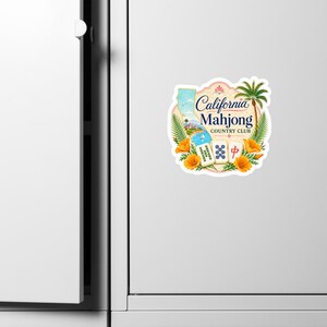May include: A sticker featuring the text California Mahjong Country Club, a map of California, a palm tree, orange poppies, and three mahjong tiles. The design includes a coastal scene with a sailboat and blue water, all framed by foliage.