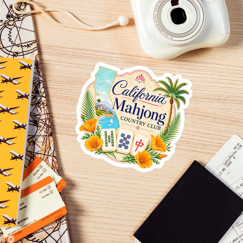 May include: A die-cut sticker featuring the text California Mahjong Country Club, a map of California, a palm tree, orange poppies, and three mahjong tiles. The design includes a coastal scene with a sailboat and a building on a cliffside.