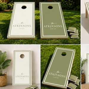 Könnte beinhalten: Ein Set aus zwei Cornhole-Boards, eines in Creme und eines in Salbeigrün, jeweils mit rechteckigem Rand, einem kreisförmigen Loch und dem Text The ATKINSONS 5.27.27. Das Set enthält mehrere kleine quadratische Sitzsäcke aus salbeigrünem Stoff.