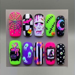 May include: A set of ten press-on nails featuring Halloween designs including a neon spiderweb, black and white checkerboard with a bat and candy corn, a Frankenstein face, green stitches with a pumpkin, a crescent moon, a cauldron, ghosts, stripes, a witch hat, and eyeballs.