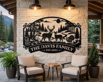 May include: A black metal wall sign featuring a laser-cut forest scene with a deer, a doe, and a turkey. The text reads THE DAVIS FAMILY EST. 2022. The sign has an arched top and decorative scrollwork on the sides, mounted on a stone wall.