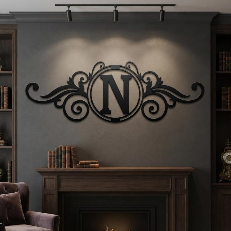 May include: A black metal wall art piece featuring a central circular frame enclosing the capital letter N, flanked by symmetrical scrolling filigree patterns that extend horizontally on both sides, mounted on a dark grey wall surface.