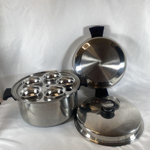 May include: A stainless steel egg poacher set featuring a deep pot with black side handles, a removable insert tray with four circular cups for poaching, and a matching stainless steel lid with a black knob handle, plus an extra lid.