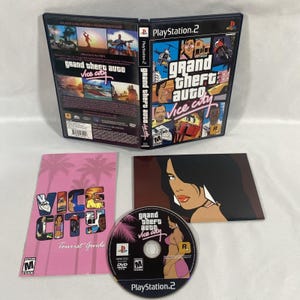 May include: A PlayStation 2 video game case for Grand Theft Auto Vice City, open to show the front and back cover art. Included is a pink Vice City Tourist Guide booklet and a game disc featuring a character illustration and the game title.