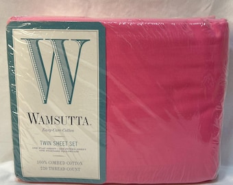 May include: A bright pink twin sheet set packaged in clear plastic. The label features a large letter W, the brand name Wamsutta, and text stating Easy-Care Cotton, 100% Combed Cotton, and 220 Thread Count, including one flat sheet, one fitted sheet, and one standard pillowcase.