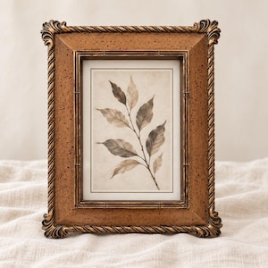 May include: A rectangular picture frame with a textured, speckled bronze finish and a rope-style border. The frame contains a print of a botanical illustration featuring a single branch with multiple leaves in shades of brown, beige, and cream.