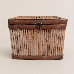 May include: A rectangular storage chest constructed from vertical bamboo stalks with a dark brown wooden frame. The lid features a hinged metal latch centered on the front, securing the top to the base. The bamboo has a natural light tan finish.