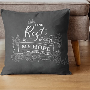 Op de afbeelding: Een grijs kussen met witte bloemenpatronen en de tekst "FIND Rest IN GOD; MY HOPE COMES FROM HIM. Psalm 62:5"