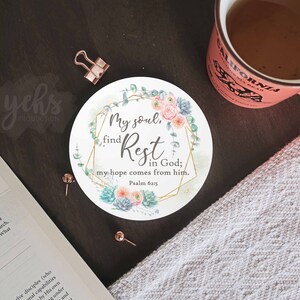 Peut inclure: Un dessous de verre rond blanc avec un cadre géométrique doré et un motif floral. Le texte "My soul, find Rest in God; my hope comes from him. Psalm 62:5" est imprimé sur le dessous de verre.