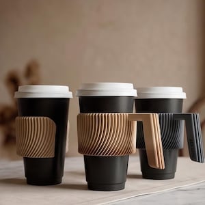 May include: Three black travel cups with white lids and textured, ribbed sleeves. The center and right cups feature integrated handles attached to the sleeves. The sleeves are light tan and dark gray, respectively, with a distinct diagonal pattern.