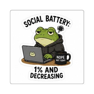 May include: A sticker featuring a green frog wearing a black hoodie, sitting at a laptop with a frog sticker on the lid. Next to the laptop is a black mug with the text NOPE. NOT TODAY. The text SOCIAL BATTERY: 1% AND DECREASING surrounds the frog.