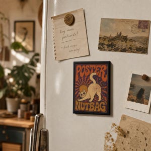 Peut inclure: Un aimant rectangulaire présentant une illustration graphique d'un chat avec le texte POSTER NUTBAG en lettres orange et jaunes sur un fond violet foncé avec des motifs de rayons de soleil et un soleil circulaire derrière le chat.