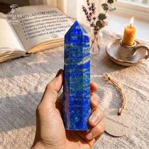 May include: A faceted lapis lazuli crystal tower with deep blue, gold, and white mineral inclusions. The stone features a polished, hexagonal point and a smooth, cylindrical body, displaying natural color variations throughout the surface.
