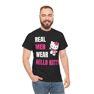 Może przedstawiać: Czarny t-shirt z napisem "REAL MEN WEAR HELLO KITTY" w kolorze białym i r&oacute;żowym. Zawiera grafikę Hello Kitty w r&oacute;żowej sukience i kokardce. Koszulka wykonana jest z miękkiego materiału.