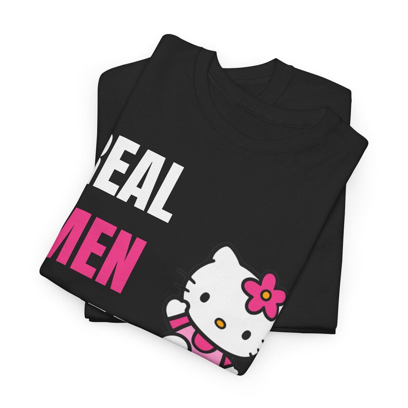 Może przedstawiać: Czarny t-shirt ze złożonym napisem "REAL MEN" w kolorze białym i r&oacute;żowym. Koszulka przedstawia grafikę Hello Kitty z r&oacute;żowym kwiatkiem.