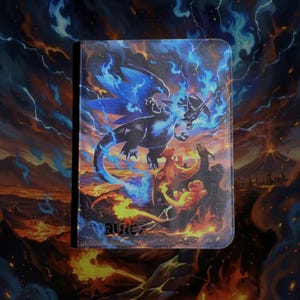 May include: A rectangular binder featuring a vibrant graphic print of a large black dragon with blue flames, surrounded by smaller orange dragon-like creatures against a fiery volcanic landscape. The word VaultX is printed in the bottom left corner.