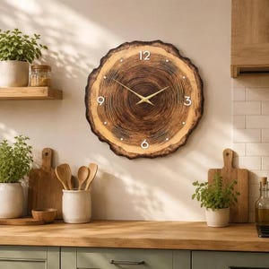 Könnte beinhalten: Eine runde Wanduhr aus einer natürlichen Holzscheibe mit sichtbaren dunkelbraunen Jahresringen. Das Zifferblatt zeigt weiße Ziffern an den Positionen 12, 3, 6 und 9 Uhr, kleine weiße Punkte für die anderen Stunden und dünne goldfarbene Metallzeiger.