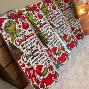 May include: A set of rectangular bookmarks featuring a green character in a red Santa suit, red bows, ornaments, and candy canes. The text reads: Maybe Christmas doesn't come from a store. Maybe Christmas... perhaps... means a little bit more. -The Grinch.