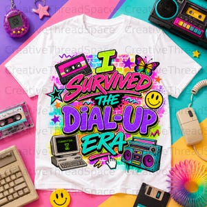 May include: A white t-shirt featuring a colorful graphic with the text I SURVIVED THE DIAL-UP ERA. The design includes a cassette tape, a computer monitor displaying a connecting screen, a boombox, a butterfly, a smiley face, and stars.