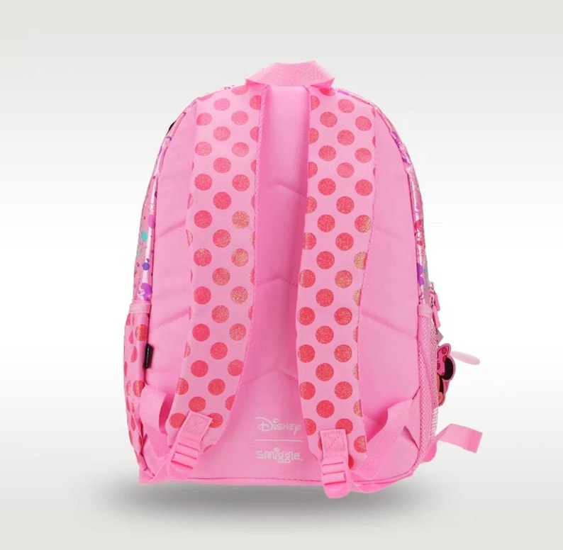 Pode incluir: Uma mochila rosa brilhante com duas al&ccedil;as acolchoadas com um padr&atilde;o de bolinhas rosa escuro. O painel traseiro &eacute; rosa s&oacute;lido com os logotipos da Disney e da Smiggle impressos em branco. A mochila inclui al&ccedil;as ajust&aacute;veis e bolsos laterais de rede.