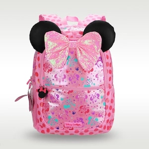 Pode incluir: Uma mochila rosa com uma estampa de Minnie Mouse em toda a superf&iacute;cie e bolinhas nas laterais. A bolsa inclui duas orelhas pretas arredondadas no topo e um grande la&ccedil;o de lantejoulas rosa iridescente centralizado entre as orelhas. O puxador do z&iacute;per tem o formato da cabe&ccedil;a da Minnie.