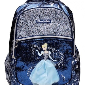 May include: A dark blue Disney Smiggle backpack featuring a glittery silver top pocket and a central compartment with a graphic of Cinderella. The bag includes a mesh side pocket, silver zippers, and a repeating white pattern of carriages and shoes.