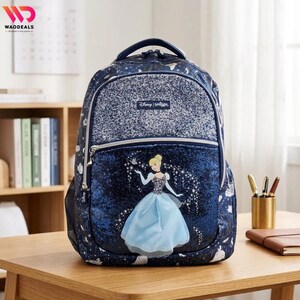 May include: A dark blue backpack featuring a glittery top panel and a lower front pocket with a graphic of Cinderella in a light blue gown. The bag has a Disney Smiggle logo patch, silver zippers, and a starry night pattern across the fabric.