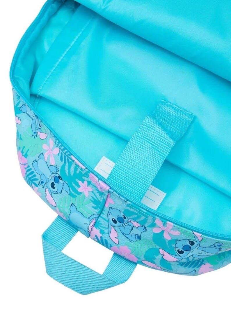 Puede incluir: Un interior de mochila de color turquesa brillante con un patr&oacute;n repetitivo de personajes Stitch azules, flores de hibisco rosas y hojas tropicales verdes. La bolsa incluye una funda para port&aacute;til a juego con una correa de cierre de velcro.