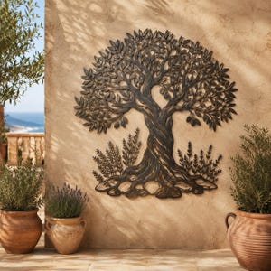 May include: A dark bronze-colored metal wall art piece depicting a stylized olive tree with a twisted trunk, detailed leaves, and small fruit clusters, featuring smaller plant sprigs at the base, mounted on a textured light brown wall surface.