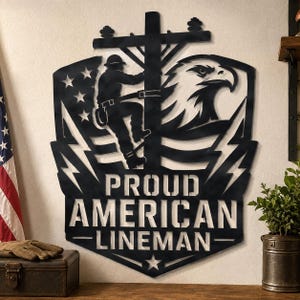 May include: A black metal wall art piece featuring a silhouette of a lineman on a utility pole, an eagle head, and the American flag. The text PROUD AMERICAN LINEMAN is cut out in the center, with lightning bolt accents and a star at the bottom.