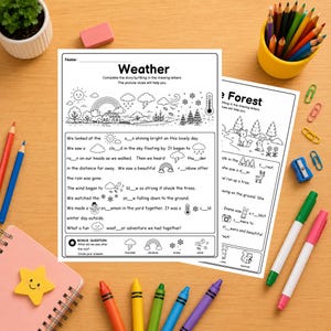 May include: Two educational worksheets titled Weather and The Forest featuring black and white line art illustrations and fill-in-the-blank sentences. The pages are surrounded by colored pencils, markers, a pink notebook, and a small potted plant.