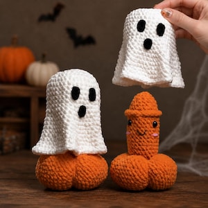 Pode incluir: Três figuras de crochê, incluindo dois fantasmas brancos com olhos e bocas pretas, e uma figura laranja de formato fálico com um rosto sorridente e bochechas rosadas. Cada figura está posicionada sobre uma base laranja redonda e texturizada.