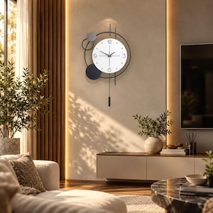 May include: A wall clock featuring a white circular face with black numerals at 3, 6, 9, and 12 o'clock. The clock is framed by black metal rings and lines, accented with gray and black circular discs, and includes a hanging pendulum.