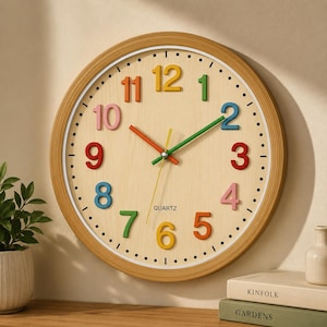 May include: A round wall clock with a light wood grain face and a matching light wood frame. The clock features raised, multi-colored numbers from 1 to 12, with a green minute hand, an orange hour hand, and a thin yellow second hand. The word QUARTZ is printed in black below the center.