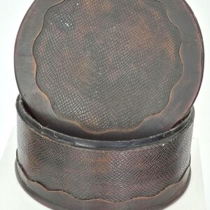 Vintage rund låda med lock har en mörkbrun texturerad finish i reptil- eller ormskinnskonst