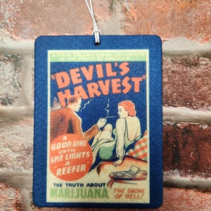 May include: A blue car air freshener with a vintage style illustration of a couple smoking. The text reads "Devil's Harvest", "A Good Girl Until She Lights A Reefer", "The Truth About Marijuana", and "The Smoke Of Hell!"